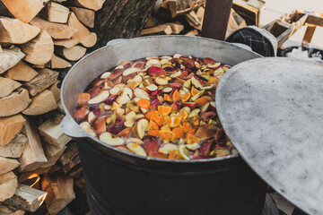 Compote cooked in big metal can cauldron outdoors