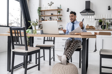 A dark-haired businessman having online meeting at his home office