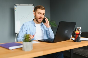 Disabled Businessman Sitting In Wheelchair Using Computer At Workplace