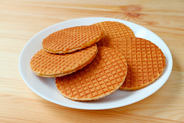 Plate of Mouthwatering Stroopwafels or Caramel Filled Traditional Dutch Waffles on Wooden Background