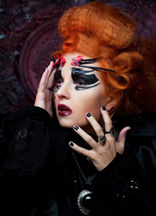 Fototapeta premium Halloween party. Young redhead woman dressed as a witch. Carnival makeup and hairstyle.