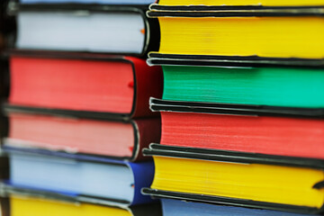 Many multi-colored books are stacked on top of each other. 