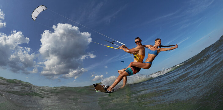 Lovely couple up on one kite board. Woman Riding On Kite surfer's Back and kiting on a sea