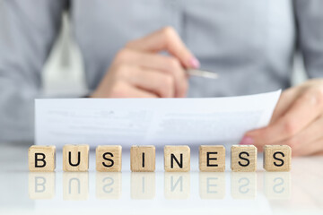 Woman manager studying documents near words business on wooden cubes closeup