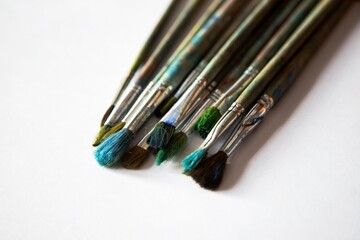 Obraz premium old worn brushes on white paper are folded in a row for drawing, a blank for a designer