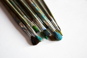 Obraz premium old worn brushes on white paper are folded in a row for drawing, a blank for a designer