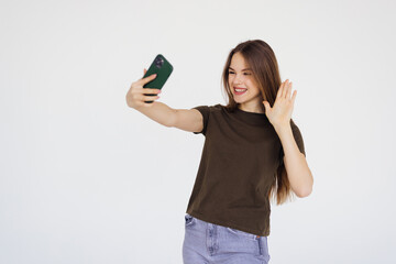 Fototapeta premium Portrait of young woman making video call or selfie and waving to the camera. Concept of communication and social media