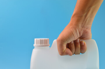 Hand holding white gallon container isolated on a blue background