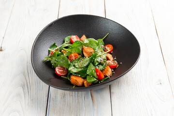 Salad with red fish and tomatoes in a plate. On a light background.