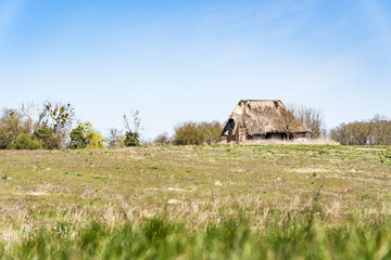 Ruin of old farmhouse on a green field in sunny daylight conditions