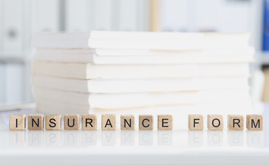 Insurance form is written on wooden cubes near documents closeup