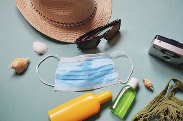 Summer travel 2022 during covid pandemic. Sun hat, sunglasses, coronavirus face mask, sanitizer bottle and camera. Lifting covid-19 restrictions