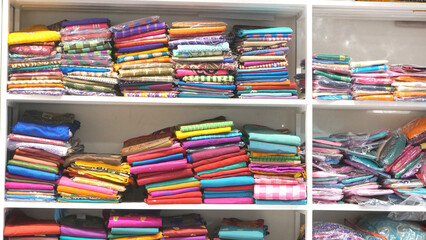 Colorful sarees or saris are arrange on racks and display in a retail shop, for use as indian textiles background.