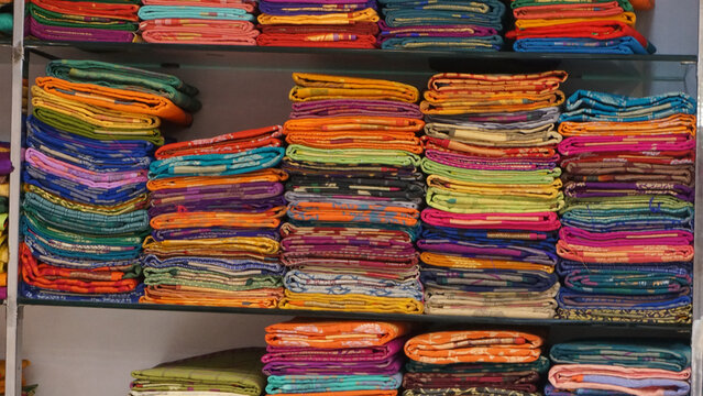 Colorful sarees or saris are arrange on racks and display in a retail shop, for use as indian textiles background.