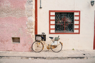 bicycle leaning against a pale pink beautiful wall with window atmospheric shabby house in mexican vibe atmosphere of freedom and poverty. Mexica composition