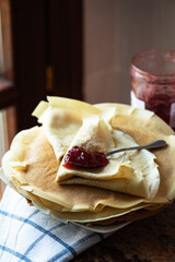 Thin crepes and strwberry jam served on a plate. Rustic style.