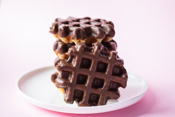 Stack of chocolate waffles. Close up and pink background.