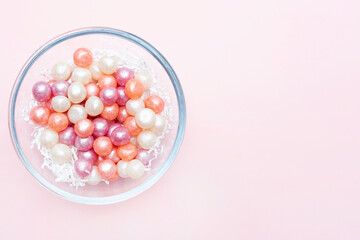Round candies and place for text. Pink background. Sweets in a glass bowl. Copy space. Flat lay. Top view. Candy pearls. Holiday invitation. Beautiful sweets.