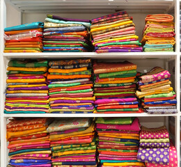 Colorful sarees or saris are arrange on racks and display in a retail shop, for use as indian textiles background.