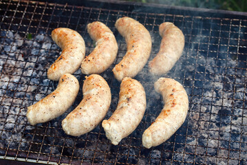 Sausage grilling, view from above on grilled sausages on grate closeup, homemade chicken sausages grilling on barbecue.