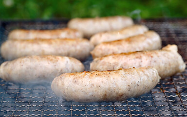 Chiken sausages cook on grill. Barbeque grill with sausages. Juicy sausages roasted on grate, cooking on charcoal and grill.