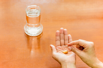 Woman hand holding medicine pills with glass of water.