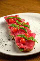 Bruschetta with red pickled meat on a white plate