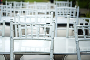 Set of white chairs leaning on dining table, during the restaurant is closed. Object equipment photo. Selective focus.