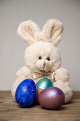 stuffed rabbit with colored eggs on a wooden board, easter special