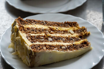 The best homemade cake you'd ever want to eat, made with walnuts, topped with white chocolate and sprinkled with almonds, served on white plates.
