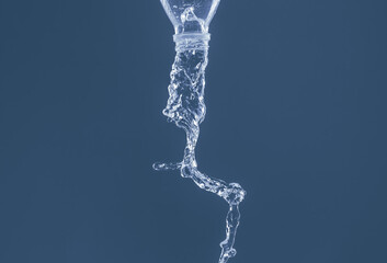 Splash of water from a bottle on a blue background. Reflection on the surface of the water.