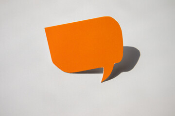 An empty dialogue made of orange paper with a speech bubble on a balloon for your design, a business concept on a white background with a hard shadow