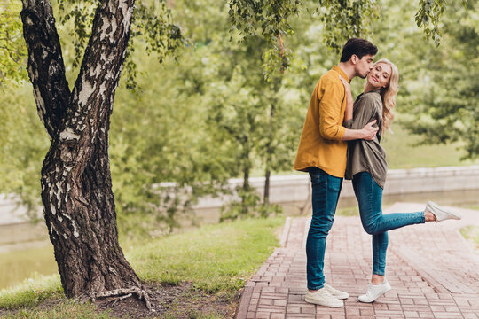 Full length body size profile side view of attractive cheerful dreamy couple hugging kissing romance time outdoors