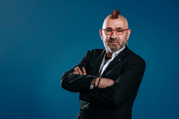 portrait of punk-style businessman looks at camera in studio shot with his arms crossed and expression of confidence
