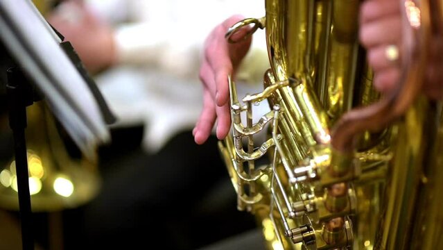 Playing a musical instrument A musician plays a tuba at a live concert. Close up of a visible tool
