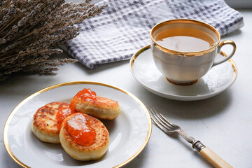 Cottage cheese pancakes, syrniki, ricotta fritters on white plate with apricot jam and sour cream. Healthy and delicious morning breakfast. 
