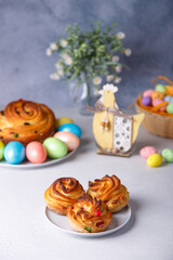 Craffin mini (Cruffin) with raisins and candied fruits. Traditional Easter Bread Kulich. In the background is a large cruffin and painted eggs on a gray background. Easter Holiday. Selective focus.