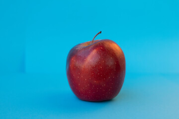 Red apple on a blue background. Ripe beautiful fruit.