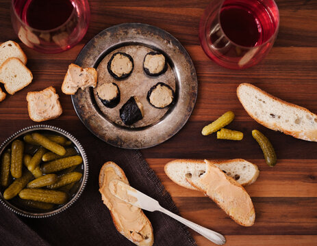 Prunes Stuffed with Foie Gras on a Metal Dish; Bread and Foie Gras; Pickles; Wine.