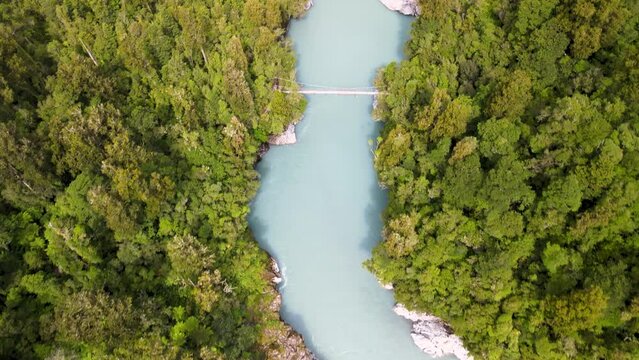 Hokitika Gorge, famous tourist attraction in New Zealand. Birds eye view of swing bridge and beautiful river surrounded by lush green native forest.