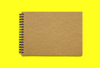Notebook made of brown paper with binding on an orange background. Dark paper notepad with free space for text. Classic bound notebook without notes top view