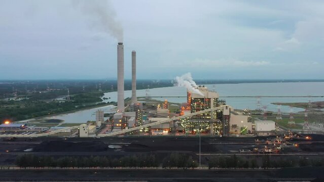 Fly around coalfield and industrial ultra-supercritical coal-fired power plant with smokes raising from chimney located at lekir bulk terminal jalan, teluk rubiah, manjung, malaysia.