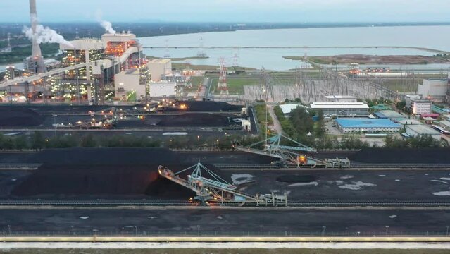 Tracking shot across coalfield and industrial ultra-supercritical coal-fired power plant with smokes raising from chimney located at lekir bulk terminal jalan, teluk rubiah, manjung, perak, malaysia.