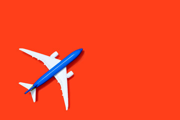 Aircraft model on a orange background with free space for text or advertising. Tourism or freight transport concept. Toy airplane on a red background with a top view