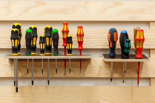 Screwdrivers in workshop. Set of Screw Drivers. Multicolored screwdrivers hanged on shelf. 