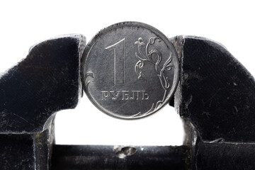 Coin one Russian ruble clamped by a black metal vice isolated on white background. Concept of...
