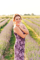 Fototapeta na wymiar Beautiful woman in a long summer dress in a lavender field in summer. Sunset landscape.