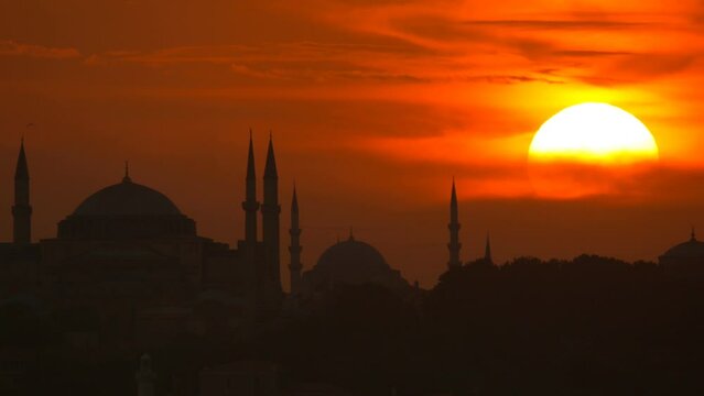 The sun sets behind silhouette of Mosques in Istanbul