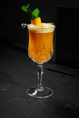 Refreshing orangeade with fresh mint in glass on black background