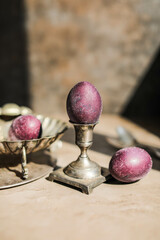 Beautiful purple eggs with shining glitter in vintage crockery. Unusual Easter egg decoration.